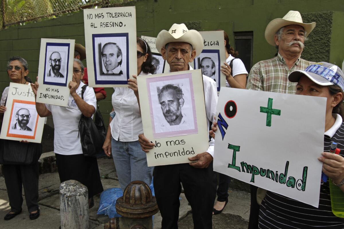 Protesters holding pictures slain Jesuit priests in San Salvador