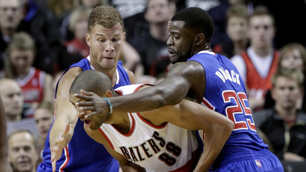 Clippers teammates Blake Griffin, left, and Reggie Bullock, right, defend against Portland Trail Blazers forward Nicolas Batum during the Clippers' preseason loss Sunday.