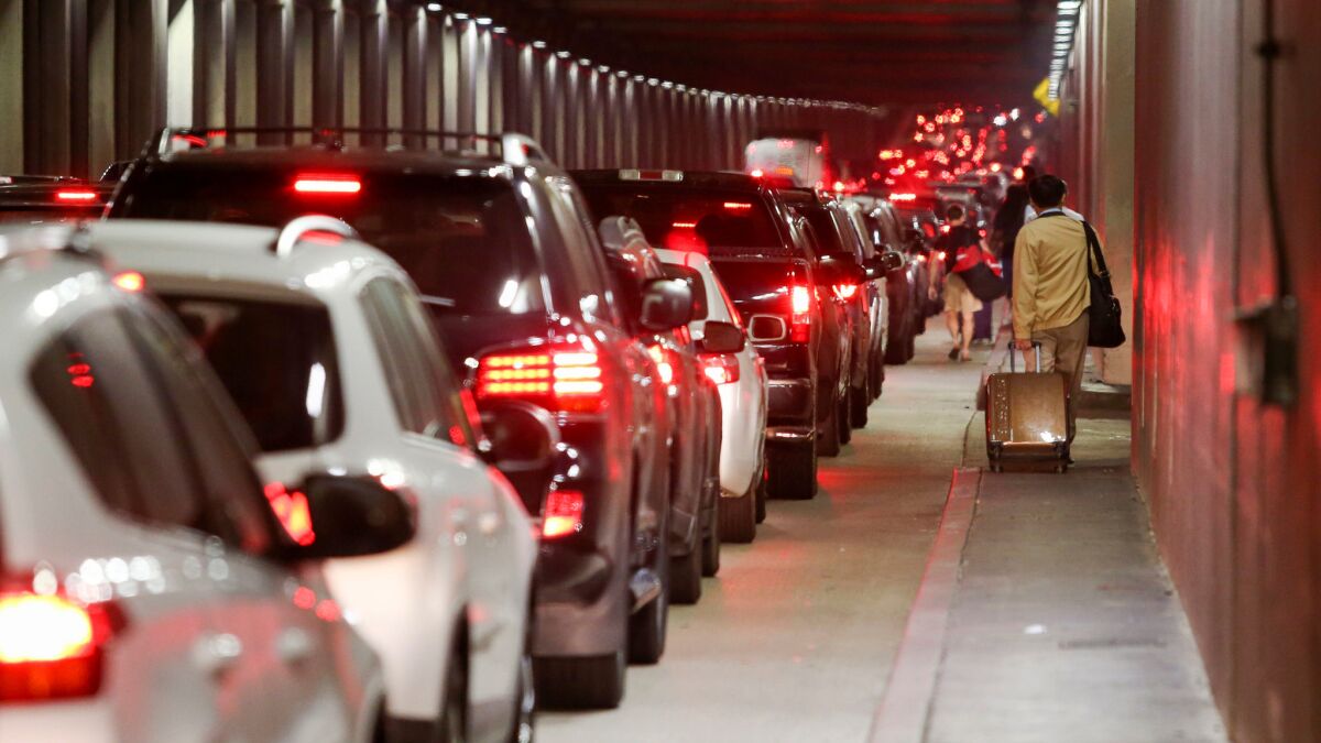 Traffic backs up through the Sepulveda Boulevard tunnel as travelers pull their luggage toward LAX, where false reports of a gunman grounded flights and caused mass panic.