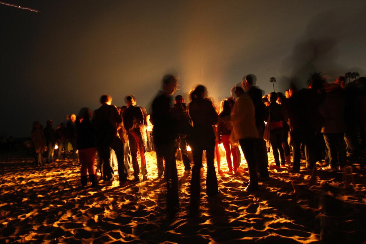 Beachgoers gather around a fire at Corona del Mar State Beach in Newport Beach in 2013. After two years of debate, the California Coastal Commission has agreed to let Newport Beach maintain 32 wood-burning fire rings and 32 that use cleaner-burning charcoal.