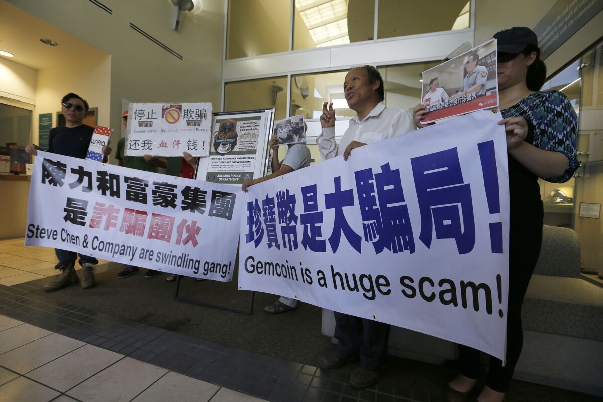 As they file reports with Arcadia police on Sept. 10, Michael Liu, second from right, and other Gemcoin investors hold banners warning potential investors.