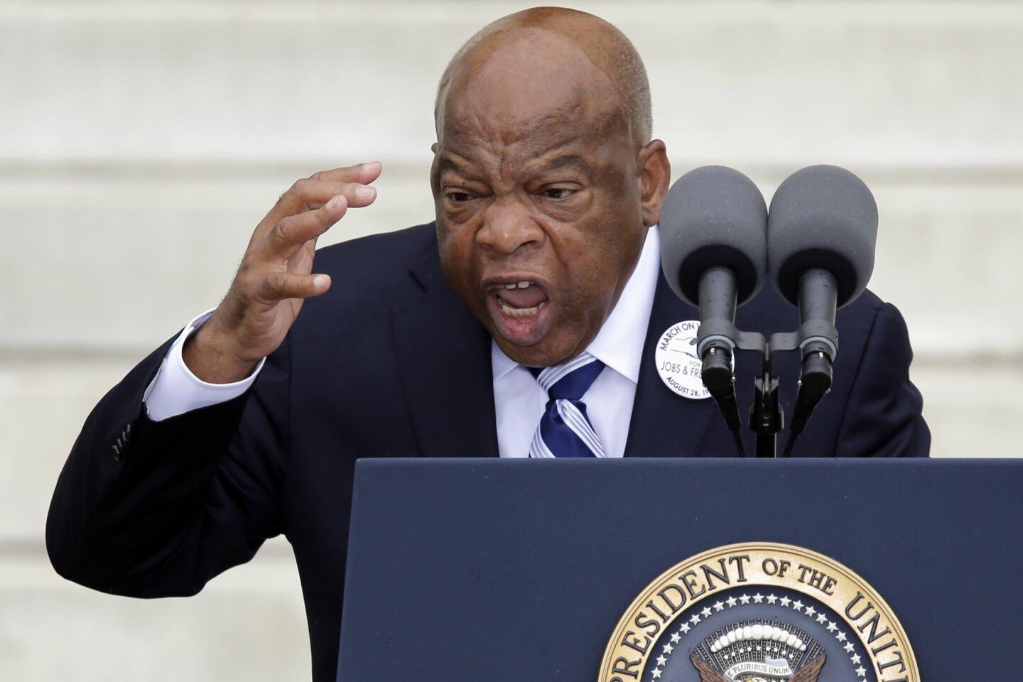 Rep. John Lewis gestures emphatically while speaking at a lectern during a commemoration of the March on Washington
