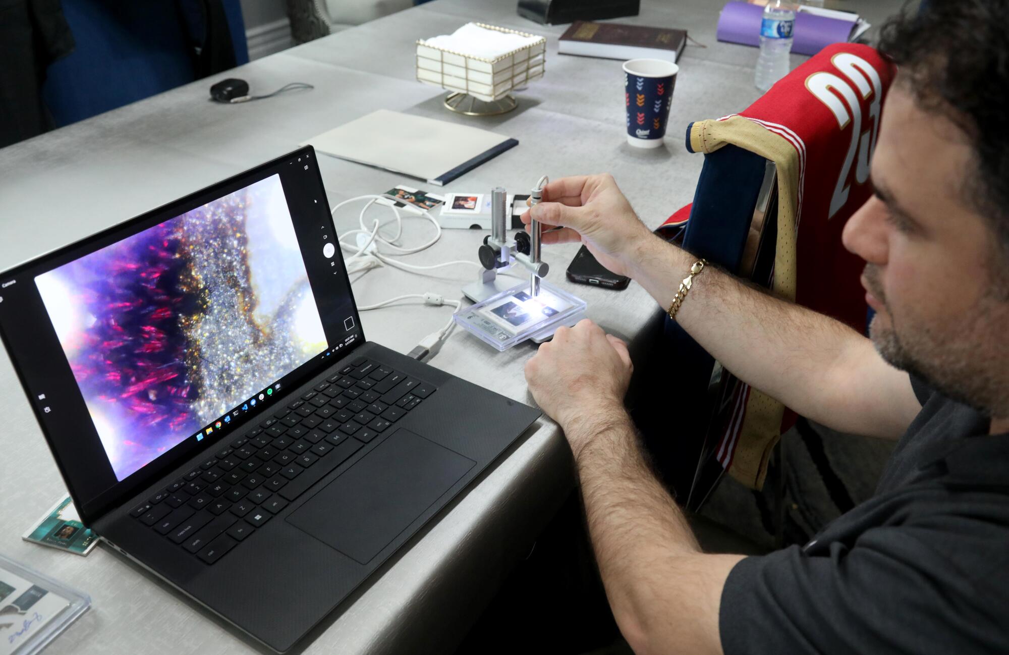 Software engineer Josh Bouganim uses a microscope to magnify a swatch of a jersey worn by LeBron James