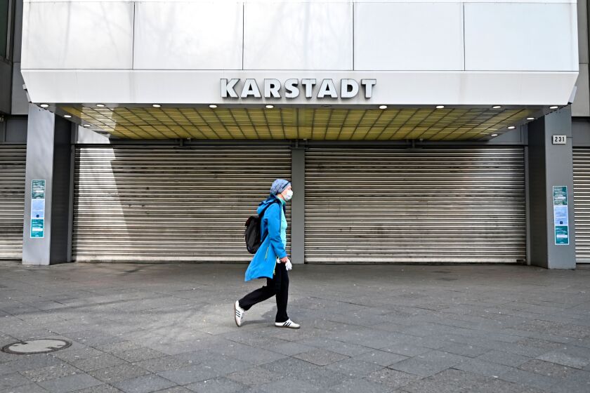 A woman wearing a face mask walks past a closed Karstadt department store in Berlin on March 18, 2020. - German leaders urged citizens to stay home, as the government announced unprecedented nationwide measures to radically scale back public life in order to slow the spread of the coronavirus. (Photo by Tobias Schwarz / AFP) (Photo by TOBIAS SCHWARZ/AFP via Getty Images)
