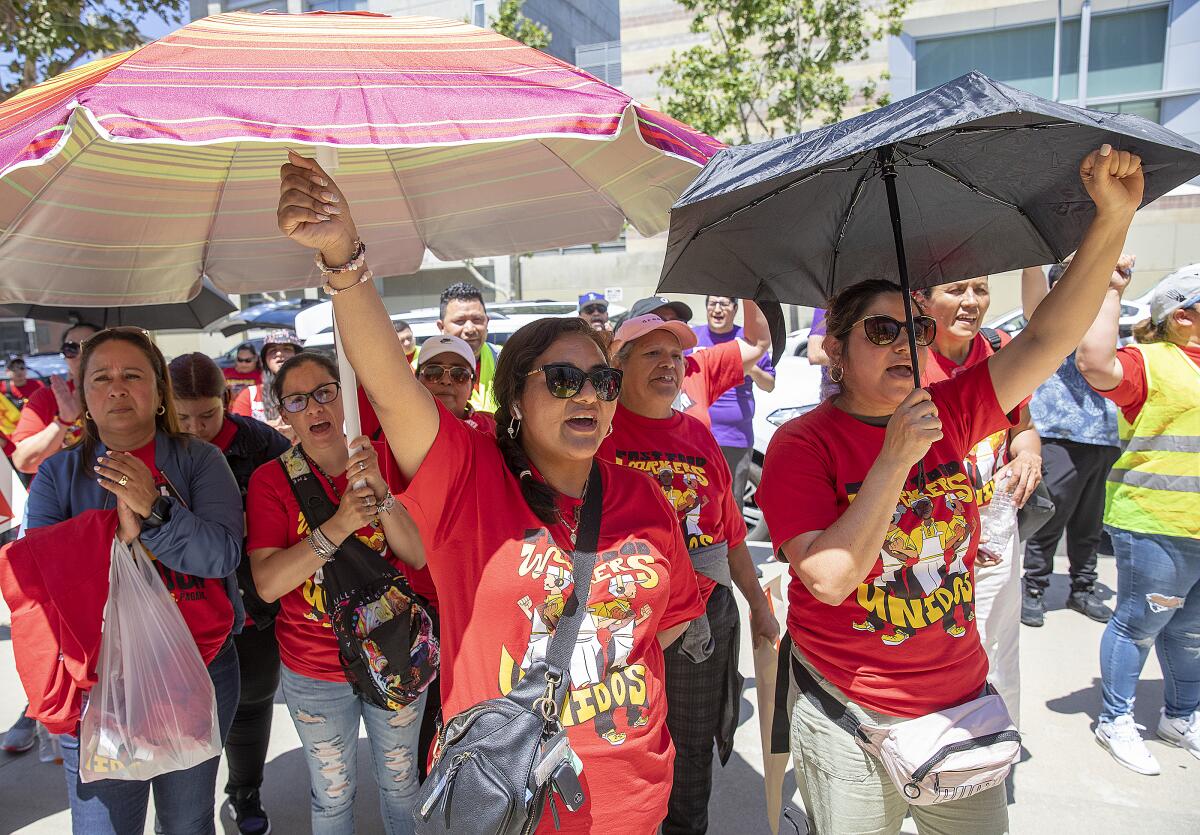 Striking fast-food workers use umbrellas to shield themselves from the sun