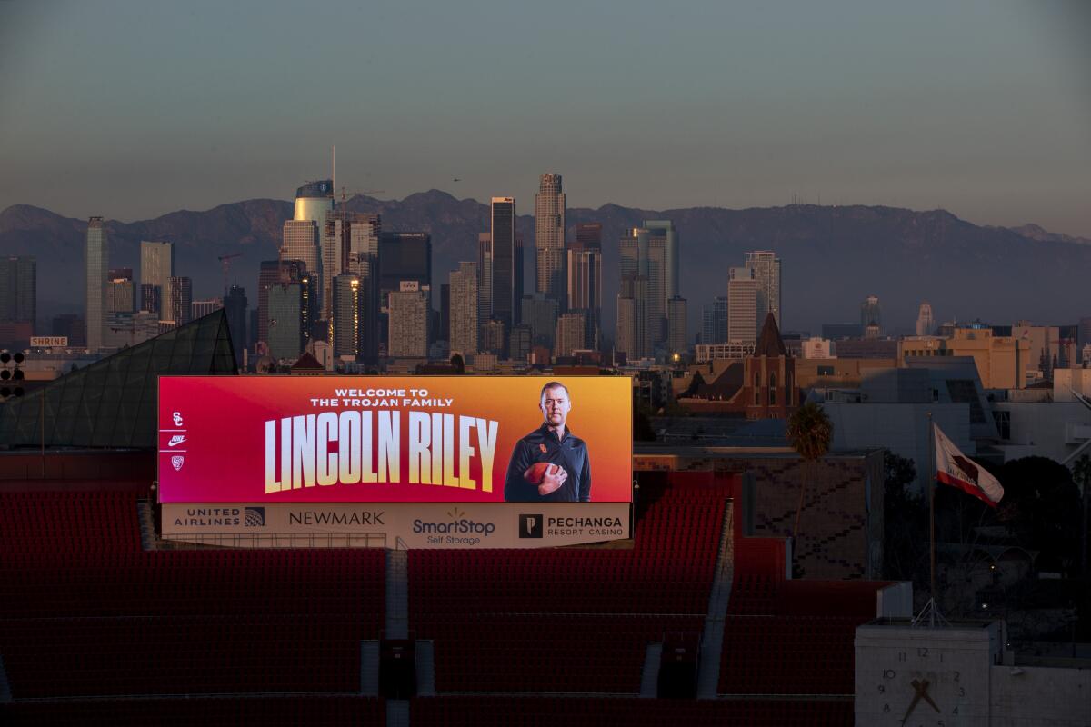 A giant video board at the Coliseum features new USC football coach Lincoln Riley with downtown L.A. as a backdrop.