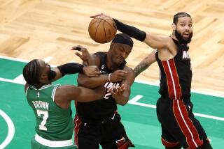 Boston Celtics guard Jaylen Brown, left, and Miami Heat forward Jimmy Butler, center, grapple for the ball.