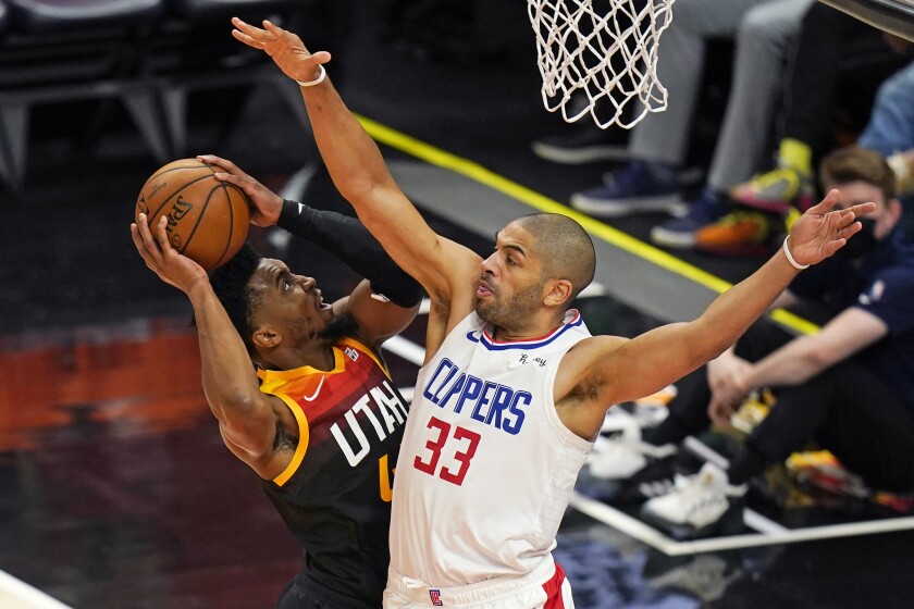 Clippers forward Nicolas Batum #33 defends as  Jazz guard Donovan Mitchell attempts a layup.
