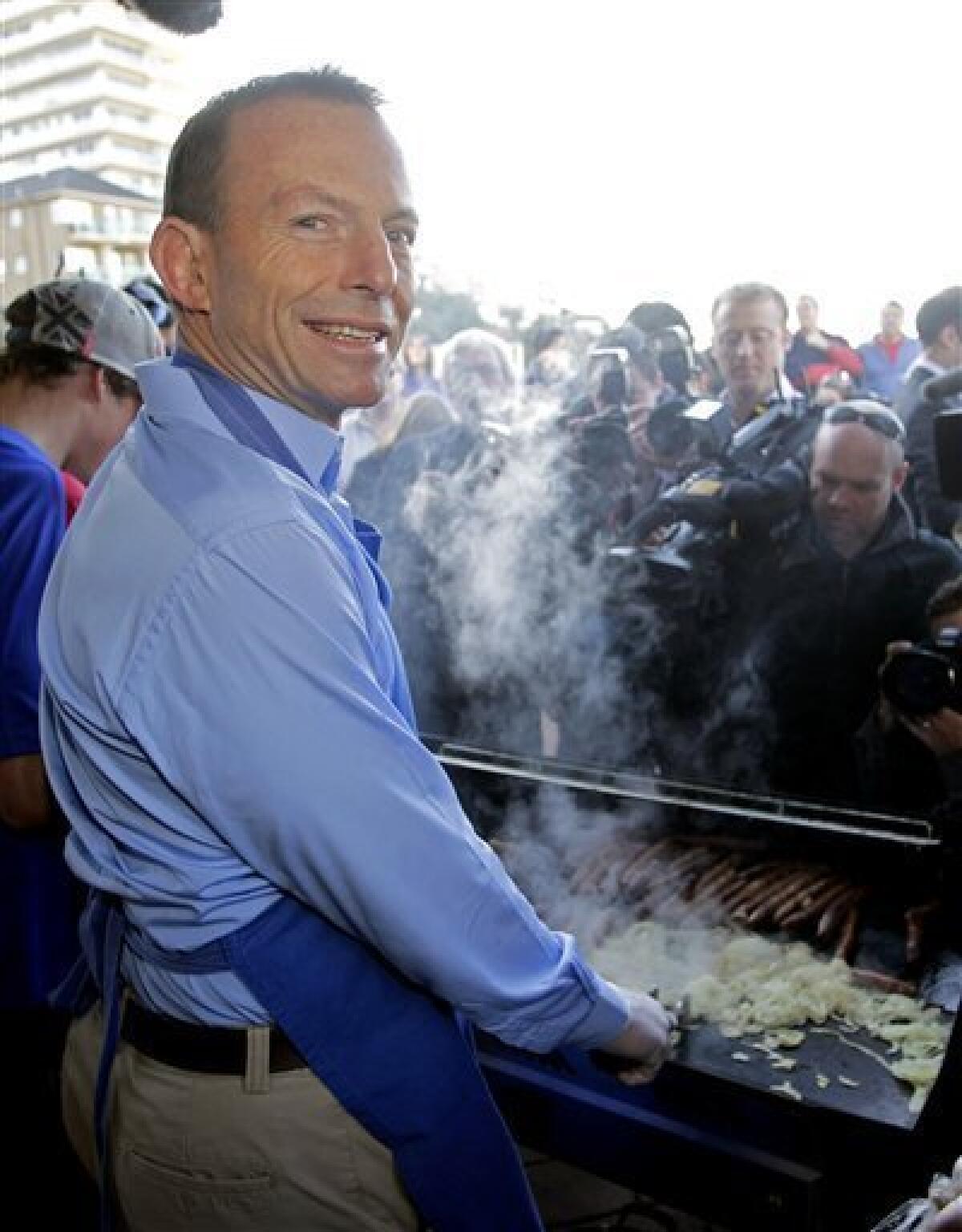 Australia's opposition leader Tony Abbott helps out at an election day sausage sizzle on Queenscliff Beach in Sydney, Australia, Saturday morning, Aug. 21, 2010. Australians go to the polls Saturday to vote in the federal election. (AP Photo/Rob Griffith)