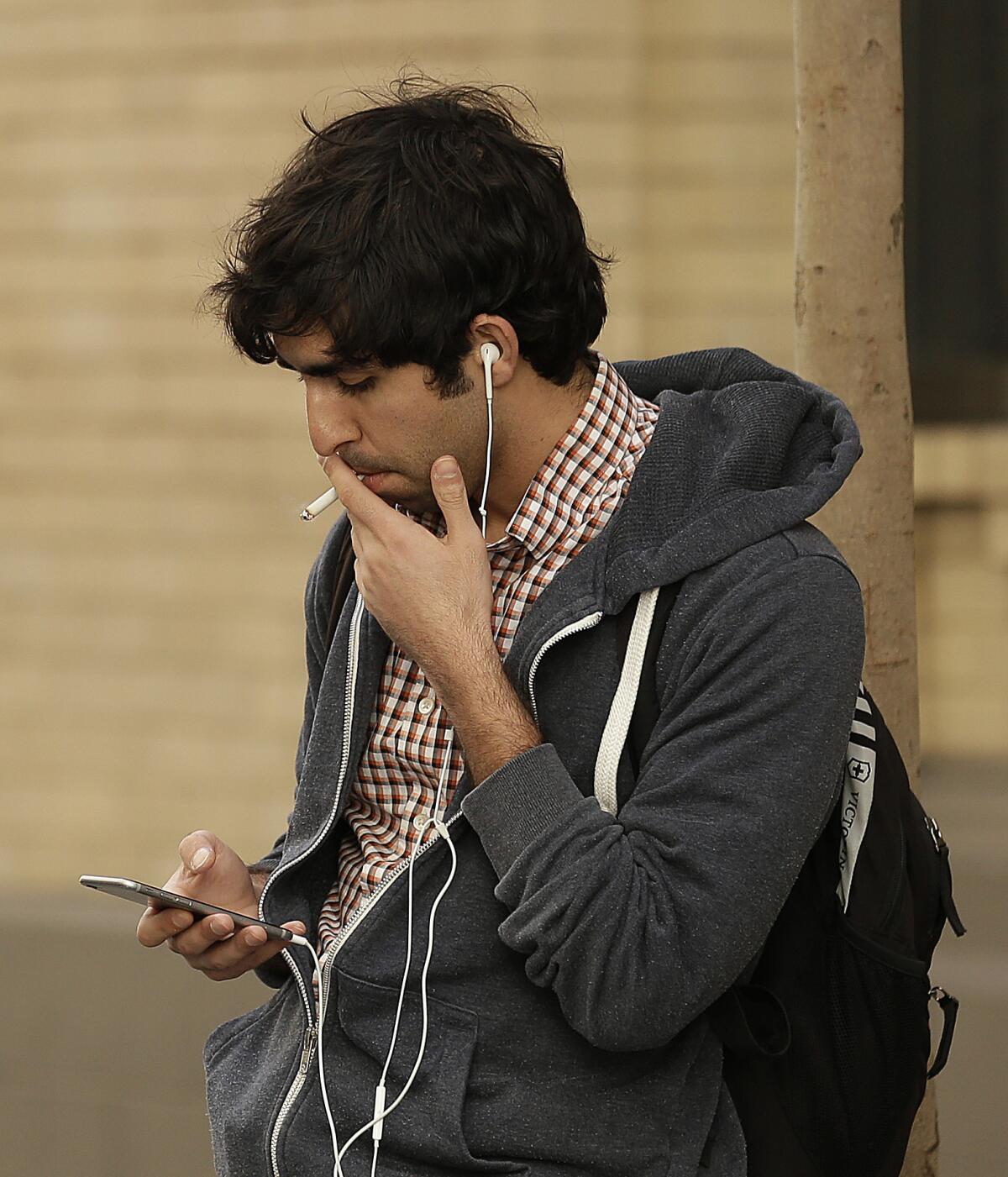 A man smokes a cigarette this week in San Francisco. The state Assembly on Thursday voted to increase the minimum age to buy tobacco from 18 to 21 and to regulate electronic cigarettes.