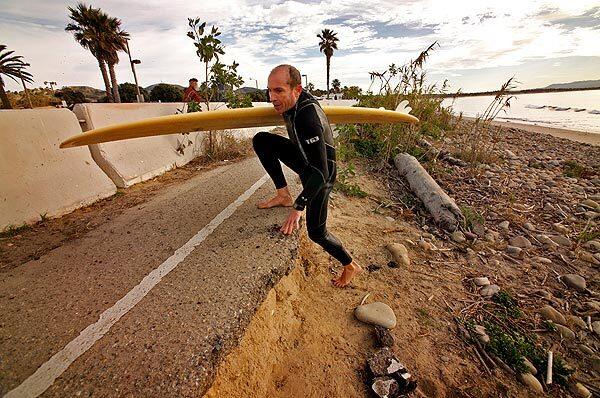 Jan Sovich climbs up to the crumbling asphalt at Surfers Point in Ventura. In a "managed retreat" from the shore, a bicycle path and parking lot are being moved 65 feet. See full story