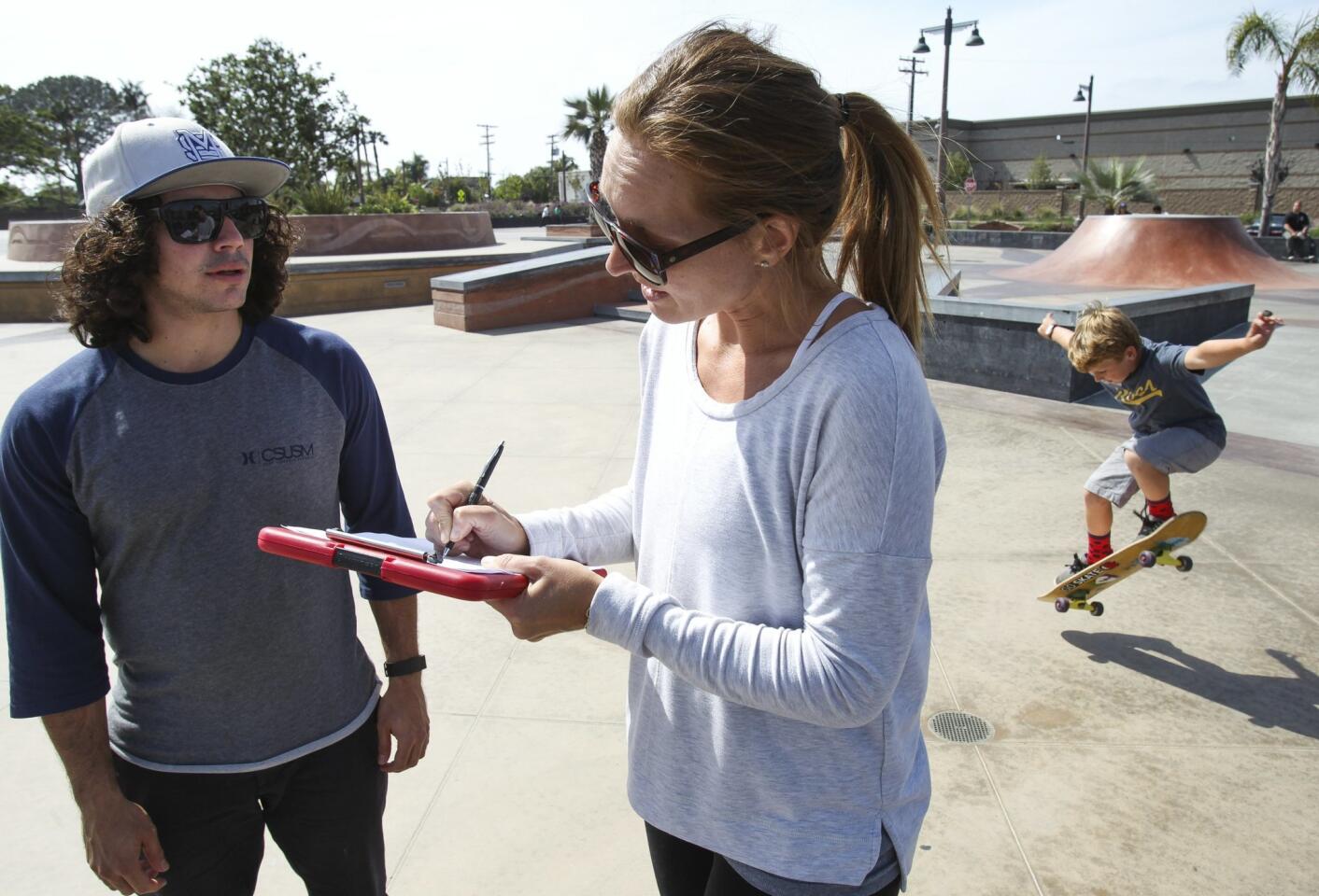 Alexandra Scully signs the paperwork for kinesiology intern Moses Wosk, 24, so that her son Ryan Scully, 8, right, can participate in CSUSM Kinesiology Department's skateboarder study.