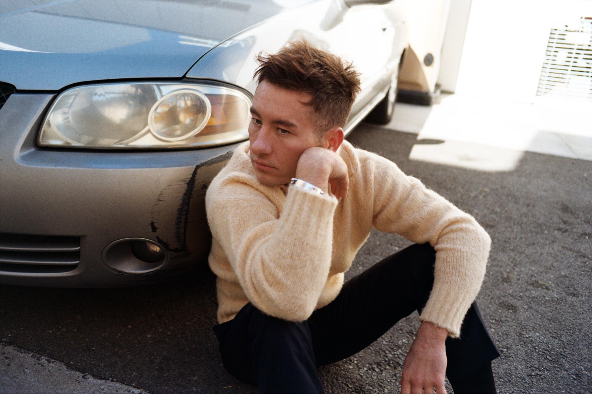 Barry Keoghan sits against a car for a portrait.