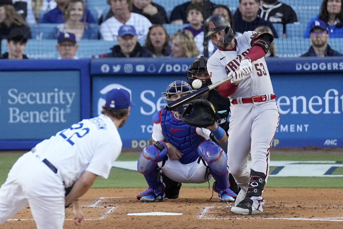 Arizona Diamondbacks' Christian Walker, right, hits a solo home run as Los Angeles Dodgers starting pitcher Clayton Kershaw, left, watches along with catcher Austin Barnes, second from left, and home plate umpire John Tumpane during the second inning of a baseball game Saturday, April 1, 2023, in Los Angeles. (AP Photo/Mark J. Terrill)