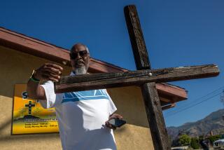SYLMAR, CA - JULY 06: Pastor Pierre Howard with one of three crosses found burning on the morning of Thursday, July 06, 2023, at Sylmar Christian Fellowship Church, Sylmar, CA. (Irfan Khan / Los Angeles Times)