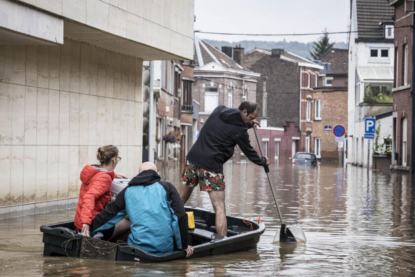 A man rows a boat down a residential street after flooding in Angleur, Province of Liege, Belgium, Friday July 16, 2021. Severe flooding in Germany and Belgium has turned streams and streets into raging torrents that have swept away cars and caused houses to collapse. (AP Photo/Valentin Bianchi)