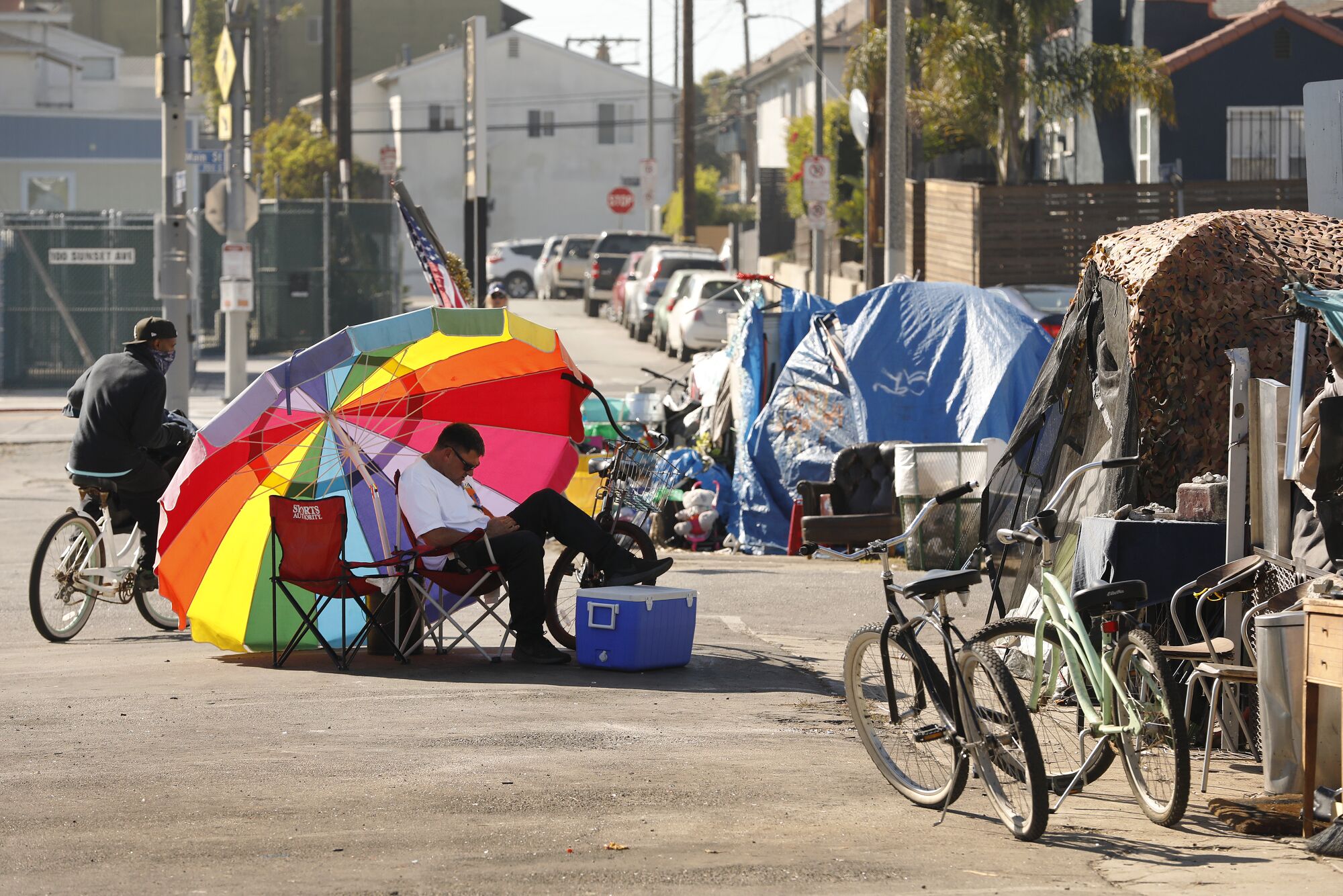 An umbrella shades Richard Thompson as he camps out with others in a Venice parking lot