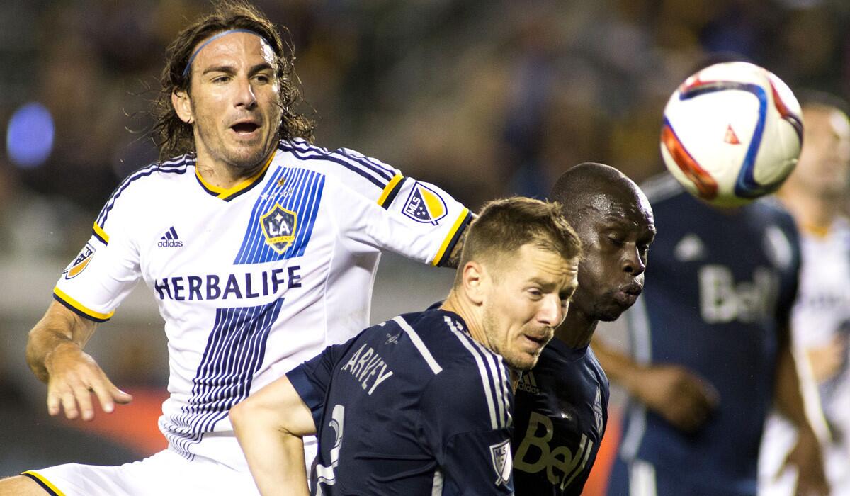 Los Angeles Galaxy forward Alan Gordon and Vancouver Whitecaps defenders Jordan Harvey, center, and Pa-Modou Kah, right, chase for the ball on June 6. The Whitecaps won 1-0, ending the Galaxy's 29-game winning streak at home.