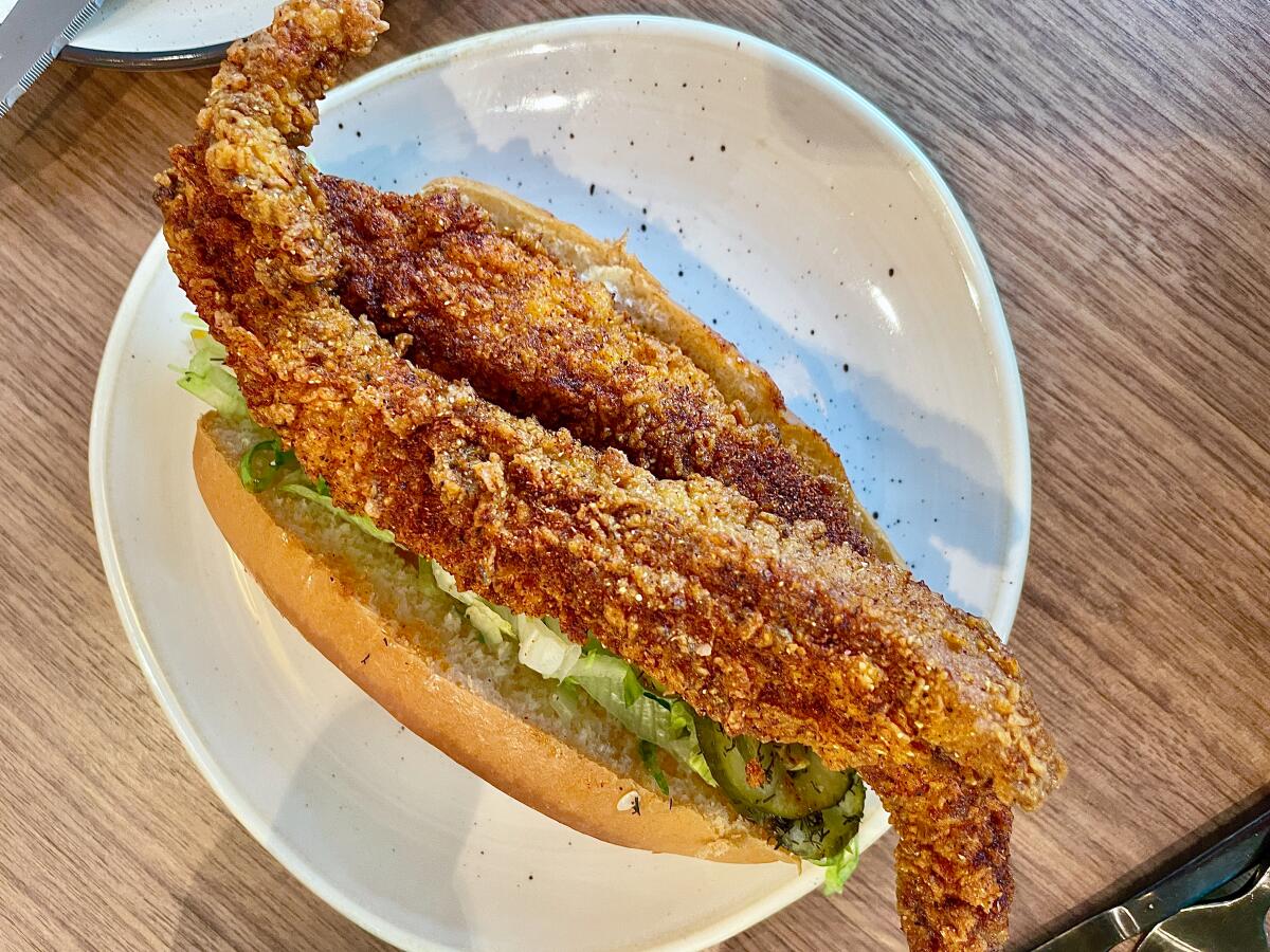 Long cylindrical fried Nashville hot catfish roll on a white plate