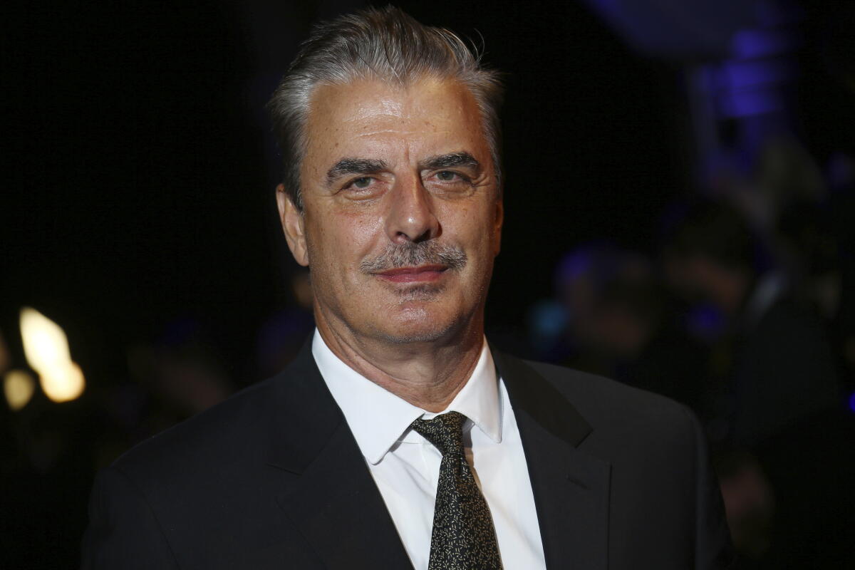 Chris Noth in a dark suit, white shirt and dark tie