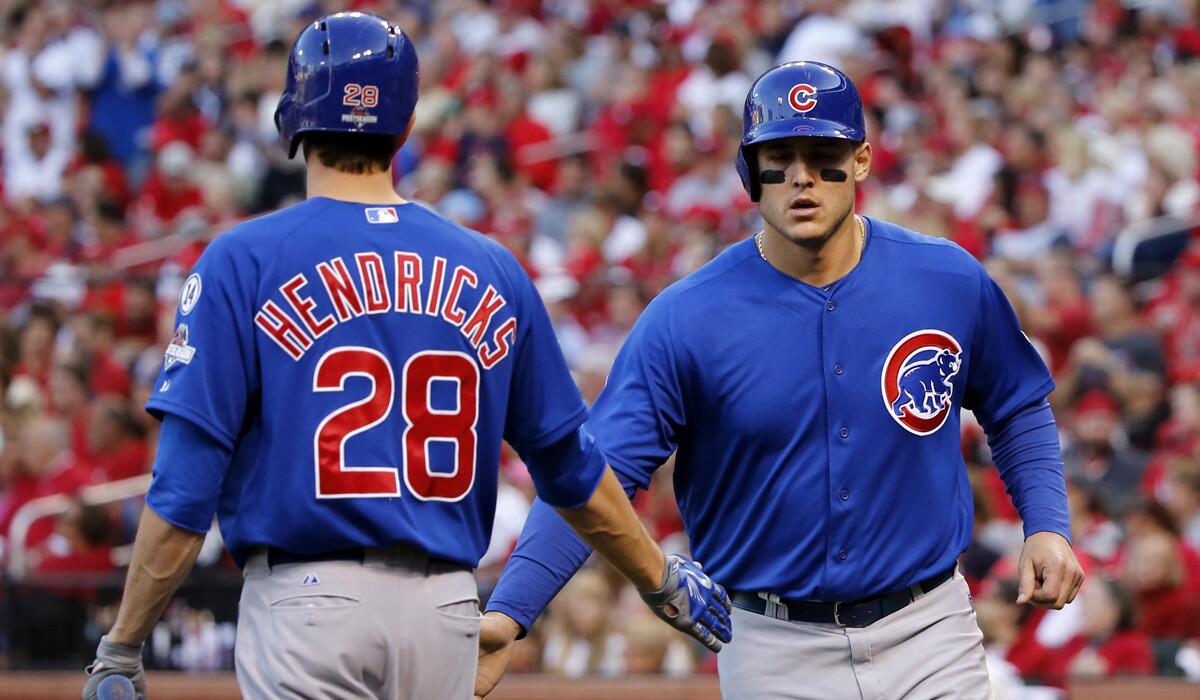 Chicago Cubs' Anthony Rizzo, right, is greeted by Kyle Hendricks after Rizzo scored during the third inning of Game 2 in theNational League Division Series on Saturday.