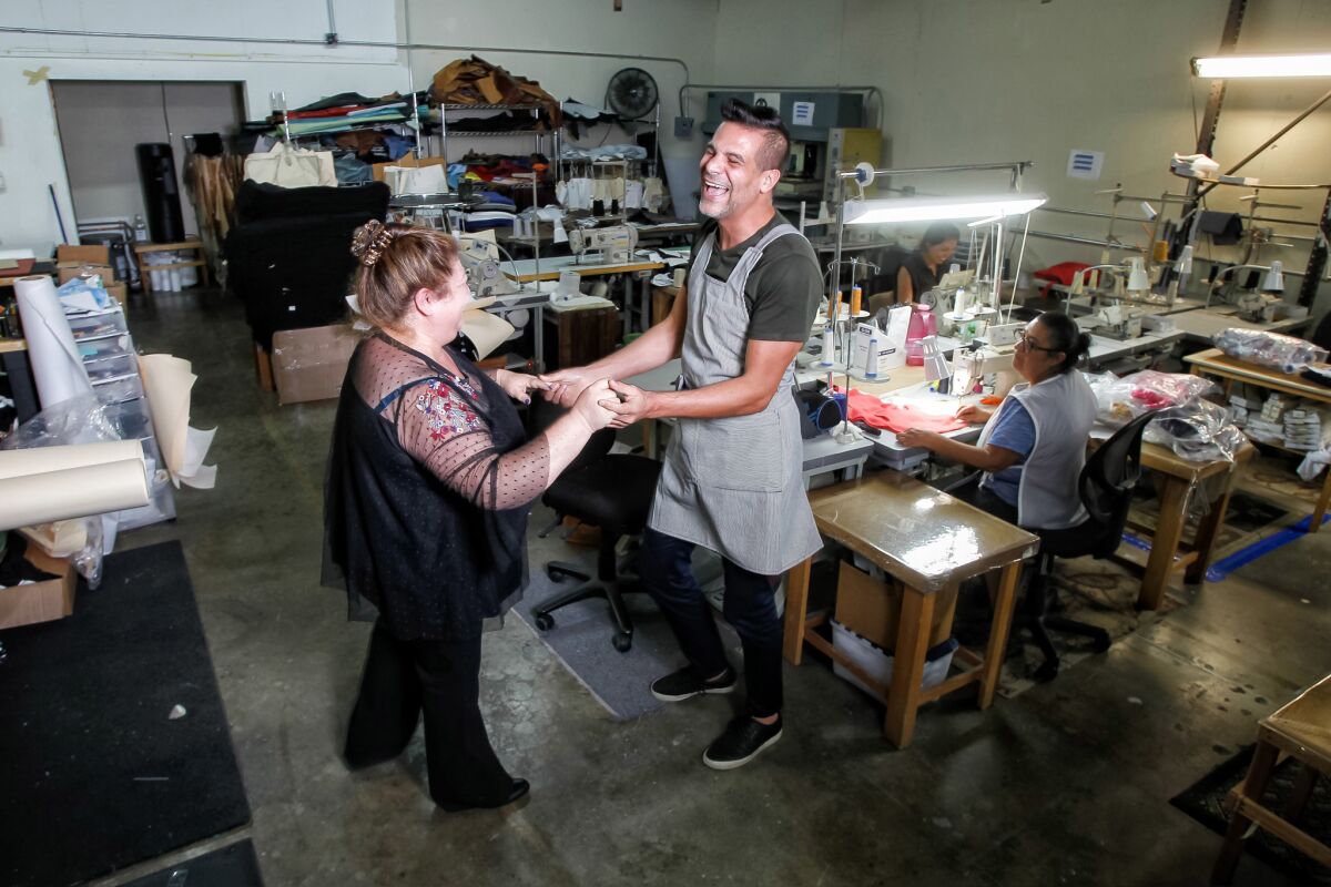 Chef Angelo Sosa (right) dances with Edith's Sewing owner Esther Cortez (left).