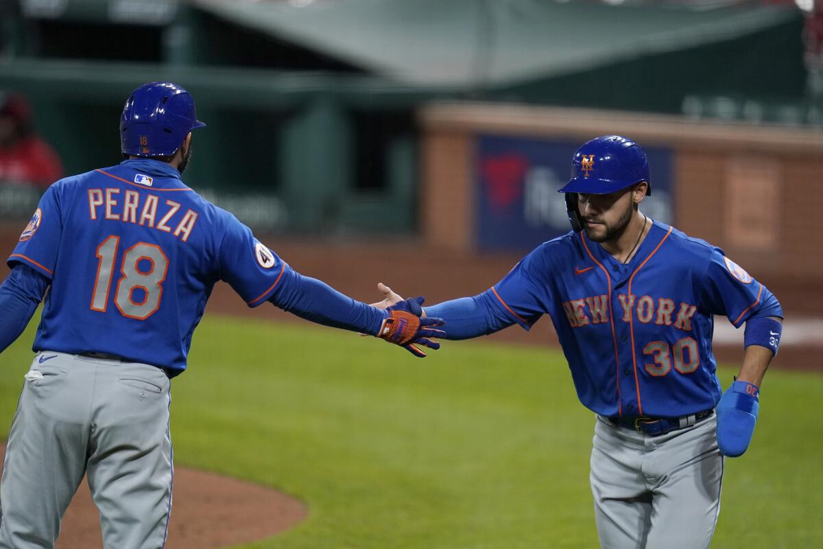 New York Mets' Michael Conforto (30) is congratulated by teammate Jose Peraza after scoring during the fifth inning in the second game of a baseball doubleheader against the St. Louis Cardinals Wednesday, May 5, 2021, in St. Louis. (AP Photo/Jeff Roberson)