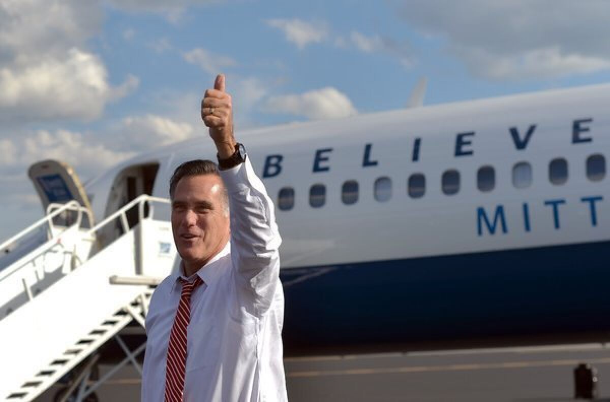 Mitt Romney gestures to supporters near his campaign plane in Weyers Cave, Va.
