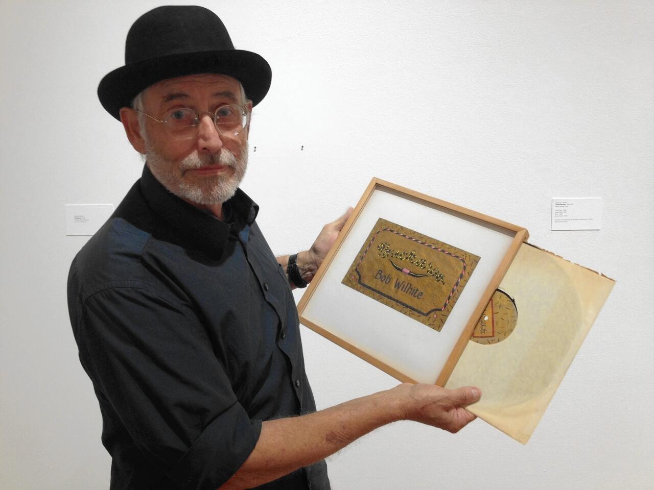 Artist and UC Irvine graduate Robert Wilhite demonstrates how his 1976 artwork, "Buckaroo," is actually a handmade record case with a real vinyl record inside. His work is on view in the University Art Gallery through Dec. 12.