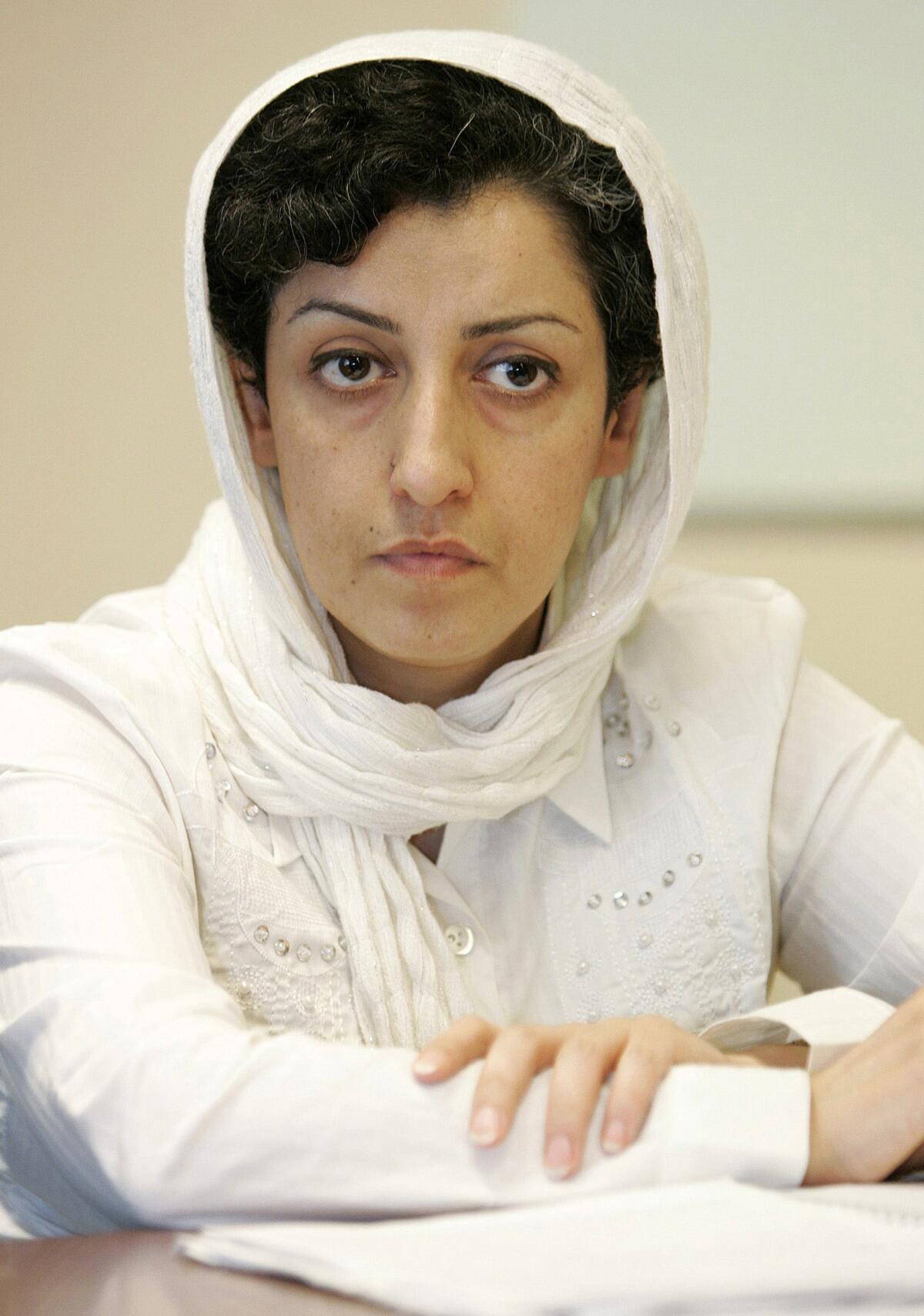 Narges Mohammadi listens with her arms rested on a table.
