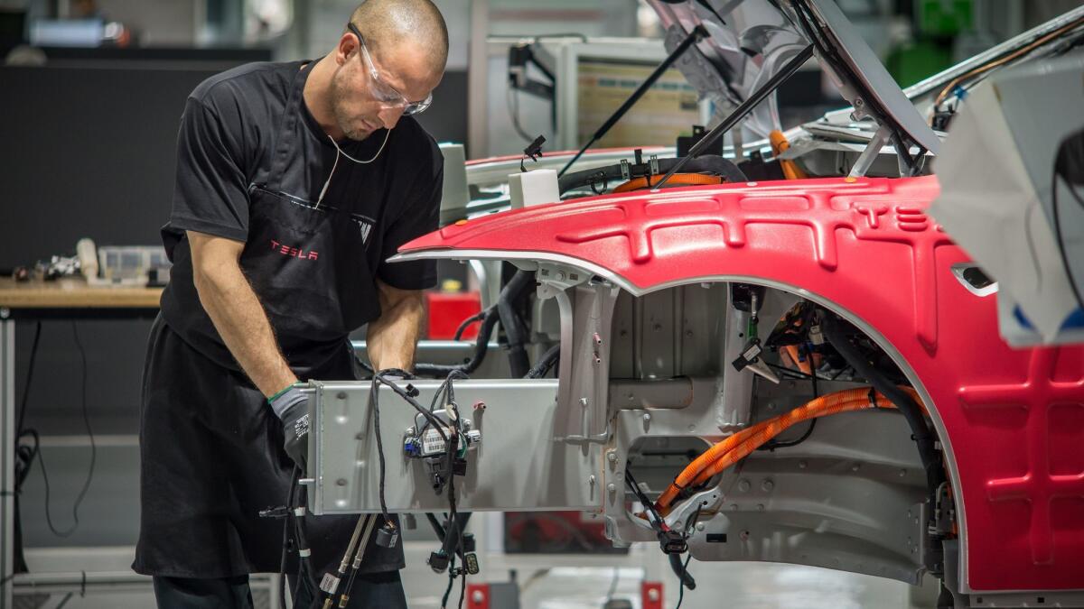 A worker assembles cars on the Tesla assembly line in 2015.