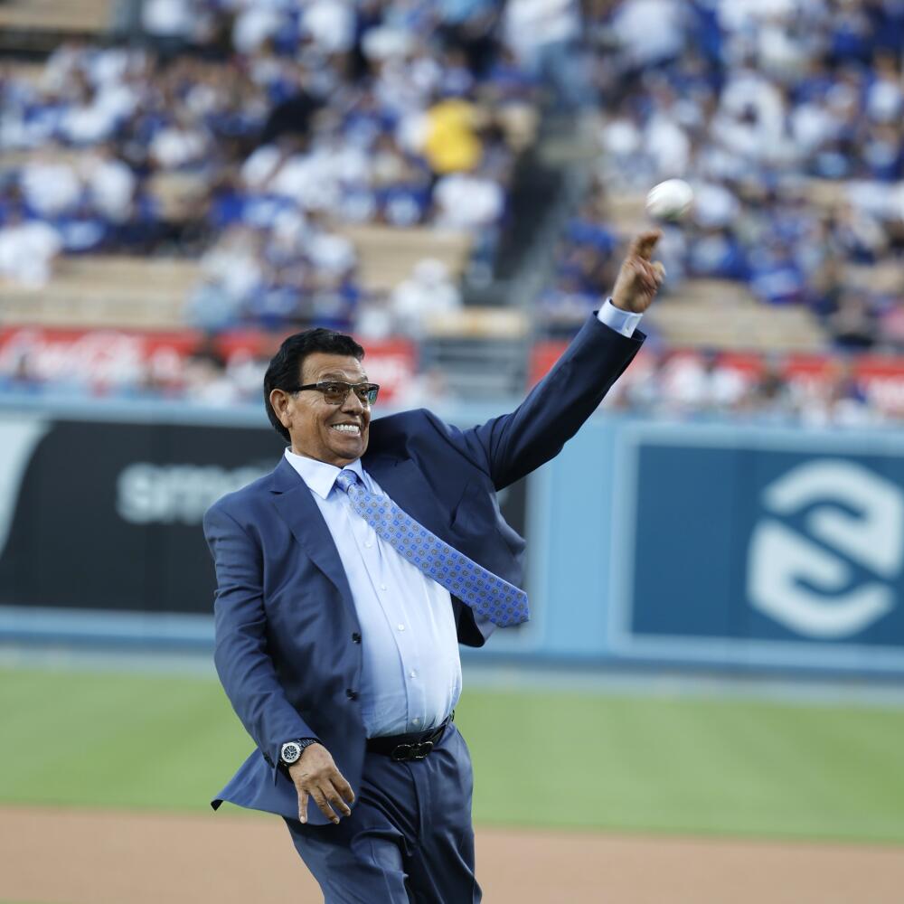 Fernando Valenzuela throws ceremonial first pitch at Dodger Stadium. He is wearing a blue gray suit with a white shirt.
