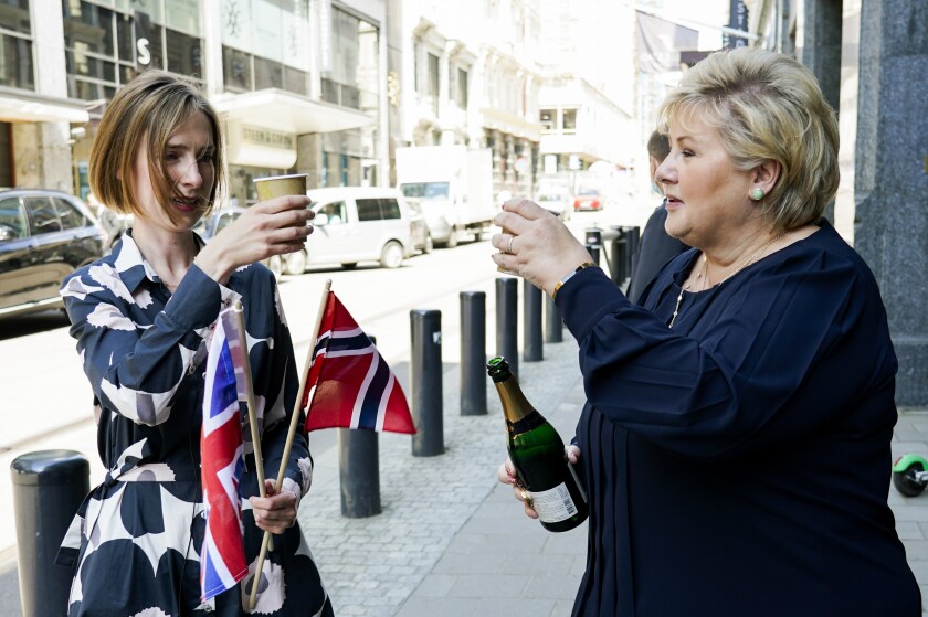 From left, Norway's Minister of Trade and Industry Iselin Nybo and Prime Minister Erna Solberg, toast, after a press conference on the status of free trade negotiations with the United Kingdom, in Oslo, Friday, June 4, 2021. Non-EU member Norway has reached a post-Brexit free trade deal with its greatest trading partner, Britain, that left the bloc last year following a 2016 referendum. Some of the differences included the import to Norway of agricultural goods such as meat and cheese, and fish exports to Britain. Norway has access to the EU’s vast common market and most goods are exempt from duties. However, the obstacle-free trading with Britain ended in late 2020. (Gorm Kallestad/NTB via AP)
