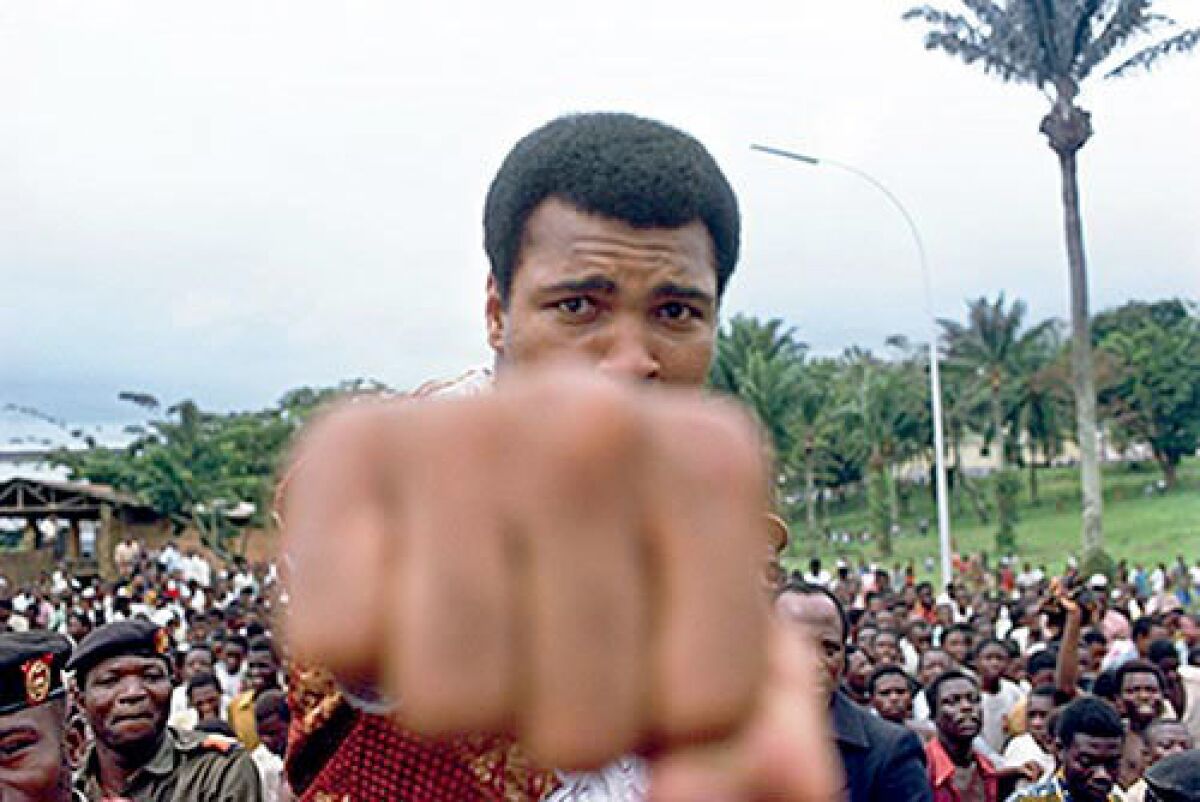 Muhammad Ali shows his fist to the camera in front of a crowd during an outing in Zaire.
