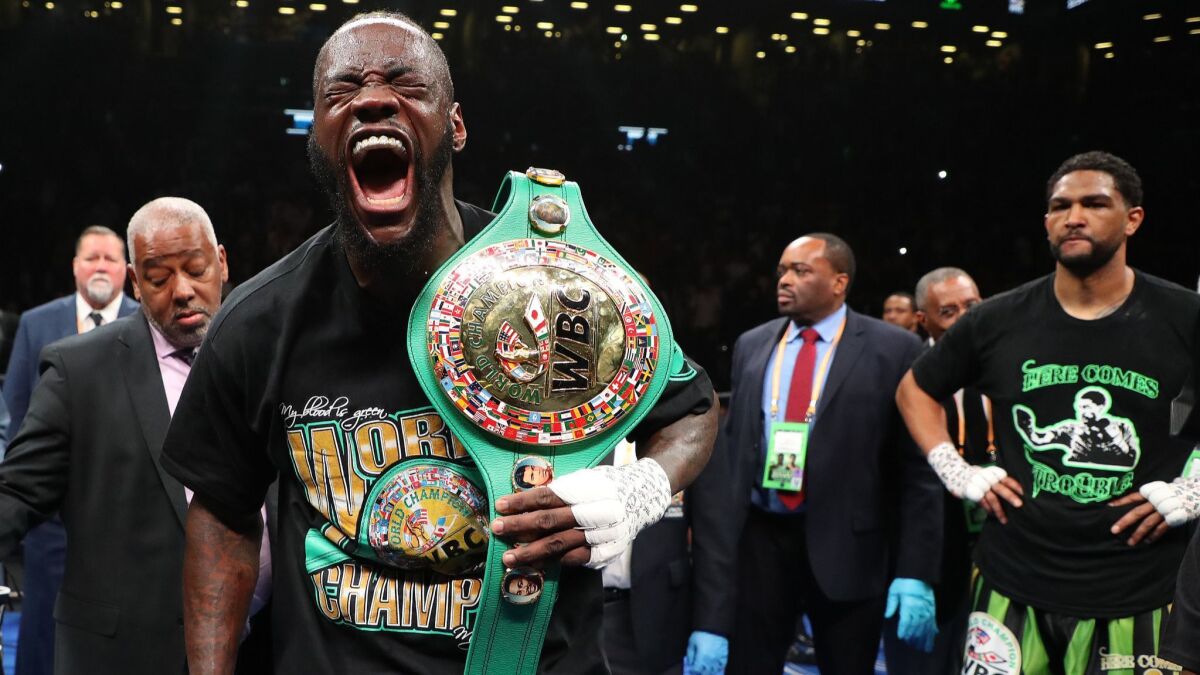 Deontay Wilder celebrates after his first round knockout of Dominic Breazeale, far right, during their bout for Wilder's WBC heavyweight title at Barclays Center on May 18 in New York City.