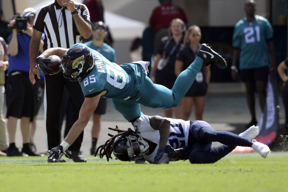 Jacksonville Jaguars tight end Dan Arnold (85) dives over Tennessee Titans cornerback Jackrabbit Jenkins for extra yardage after a reception during the first half of an NFL football game, Sunday, Oct. 10, 2021, in Jacksonville, Fla. (AP Photo/Phelan M. Ebenhack)