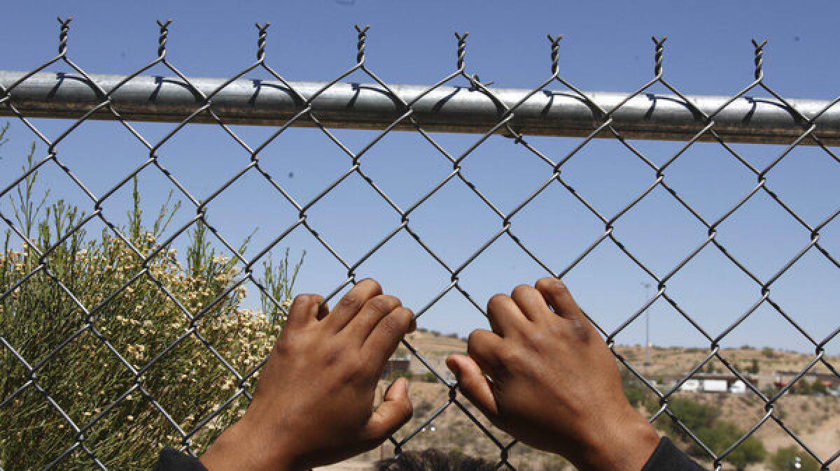 After being detained by the U.S. Border Patrol, a man rests his hands on a fence looking out to the United States from a Mexican customs station.