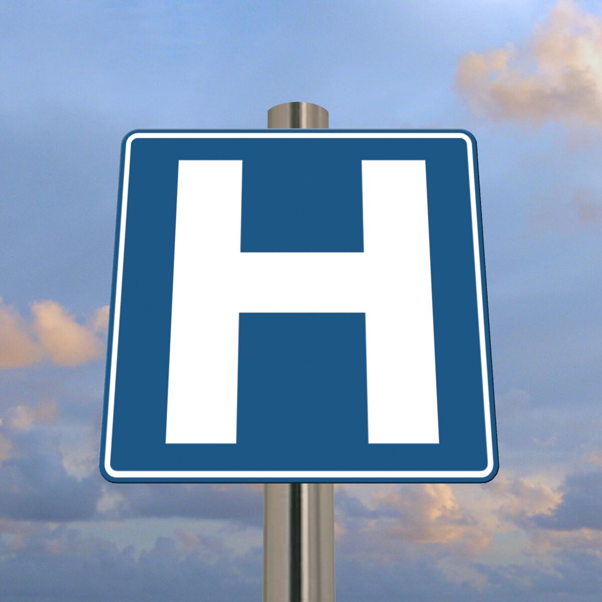A block H hospital sign against a background of a cloudy sky