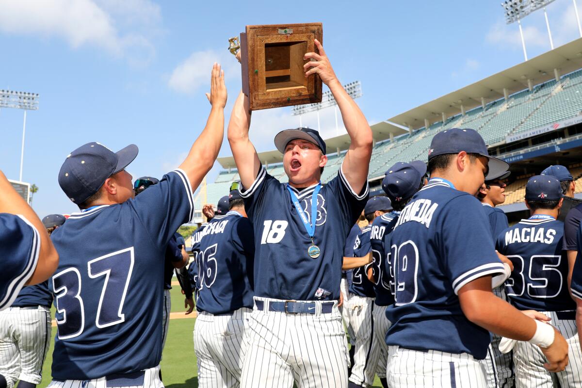 Birmingham starting pitcher Kaden Taque lifts the championship trophy while celebrating a 3-1 win over Carson.