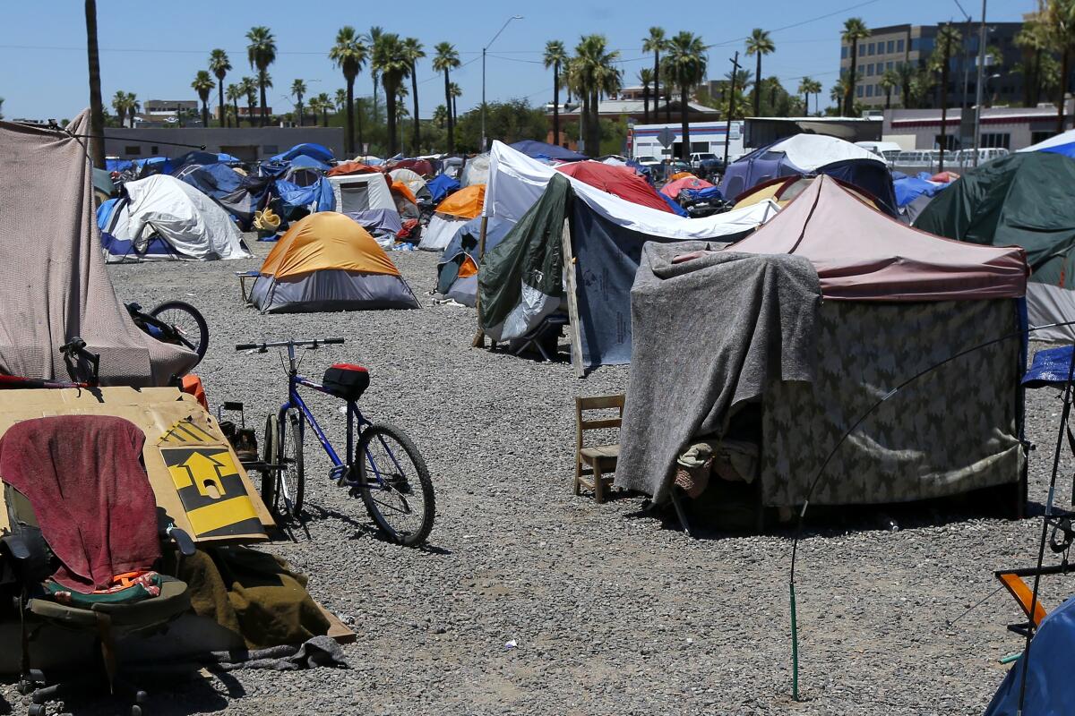 A large homeless encampment is shown in Phoenix