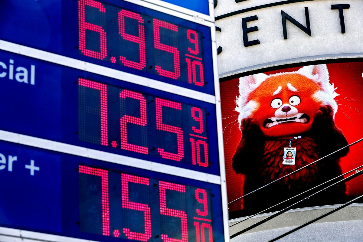 A gas station lists gas at $6.95 per gallon in front of an advertisement that includes a horrified red panda cartoon