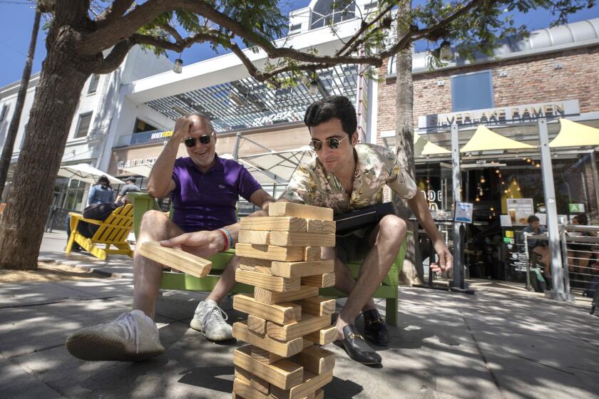 Partners Kevin Farmer, left, and Everett McCormick play a game of Jenga at the Third Street Promenade in Santa Monica