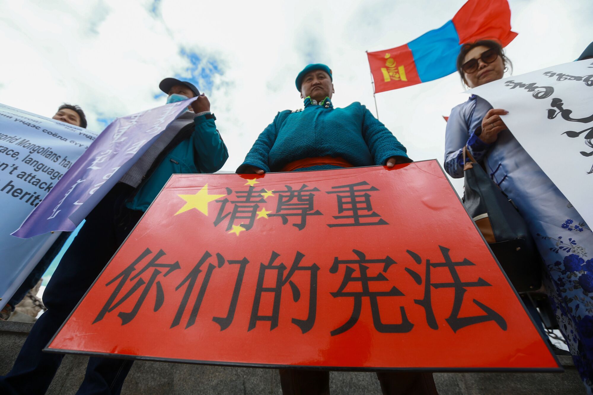 A Mongolian man holds a protest banner in the shape of China's flag that reads, "Respect your constitution." 