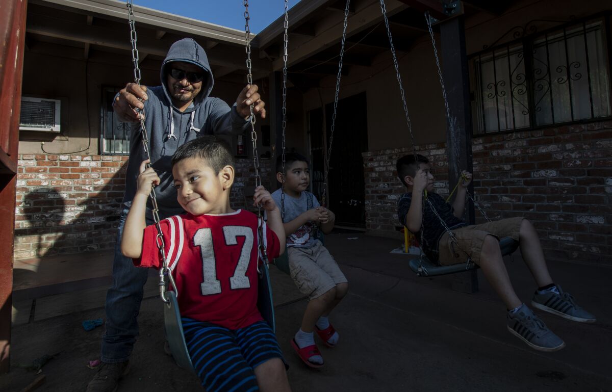 Farmworker Jose Luis Hernandez spends time with his sons Carlos, Jose and Angel outside their apartment in Stockton.