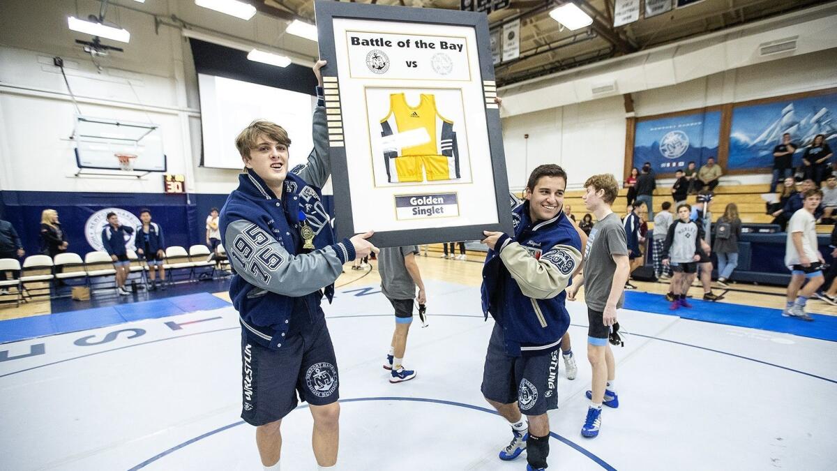 Newport Harbor High's Austin Osumi, left, and Miguel Licona hold up the Golden Singlet after beating Corona del Mar 56-18 in a Wave League match on Wednesday.