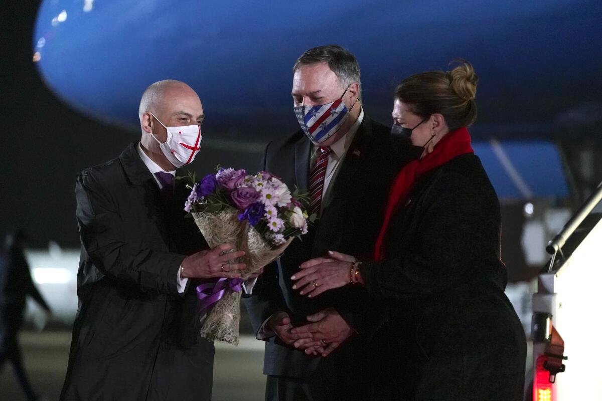Georgian Foreign Minister David Zalkaliani, left, gives flowers to Susan Pompeo as she and her husband, Secretary of State Mike Pompeo, arrive at Tbilisi International Airport in Tbilisi, Georgia, Tuesday, Nov. 17, 2020. (AP Photo/Patrick Semansky, Pool)
