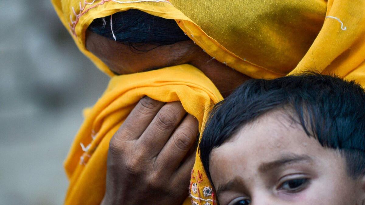 A Pakistani woman cries as she holds her child, who tested positive for HIV, in Ratodero, Pakistan.