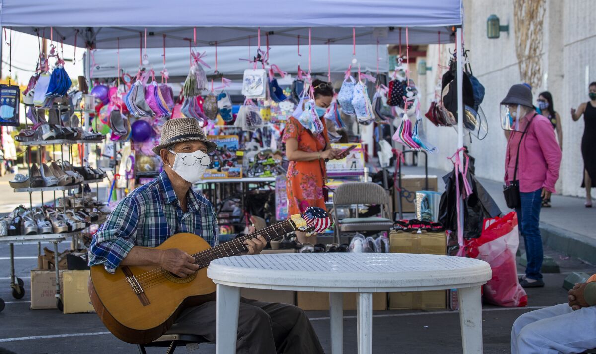 Keith Tran of Santa Ana plays a guitar while wearing a mask at the Asian Garden Mall in Westminster.