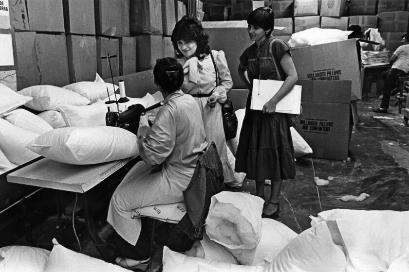 June 1983: Cristina Ramirez, center, organizer for the International Ladies Garment Workers Union, visits workers at a Los Angeles factory. This photo was published in the Aug. 7, 1983, Los Angeles Times.