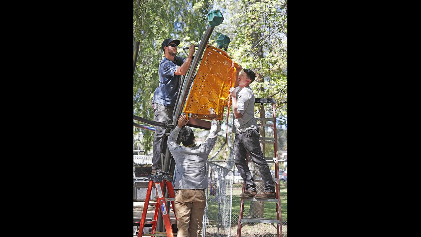 Tyler McManus, Mike Windsor, and Ryan Donahoe work together to place a large piece on a structure of GameTime playground equipment at Carr Park in Glendale on Monday, March 26, 2018. The project has had several days of delays due to rain, but if the weather holds until the project is complete, it should be open in mid April.